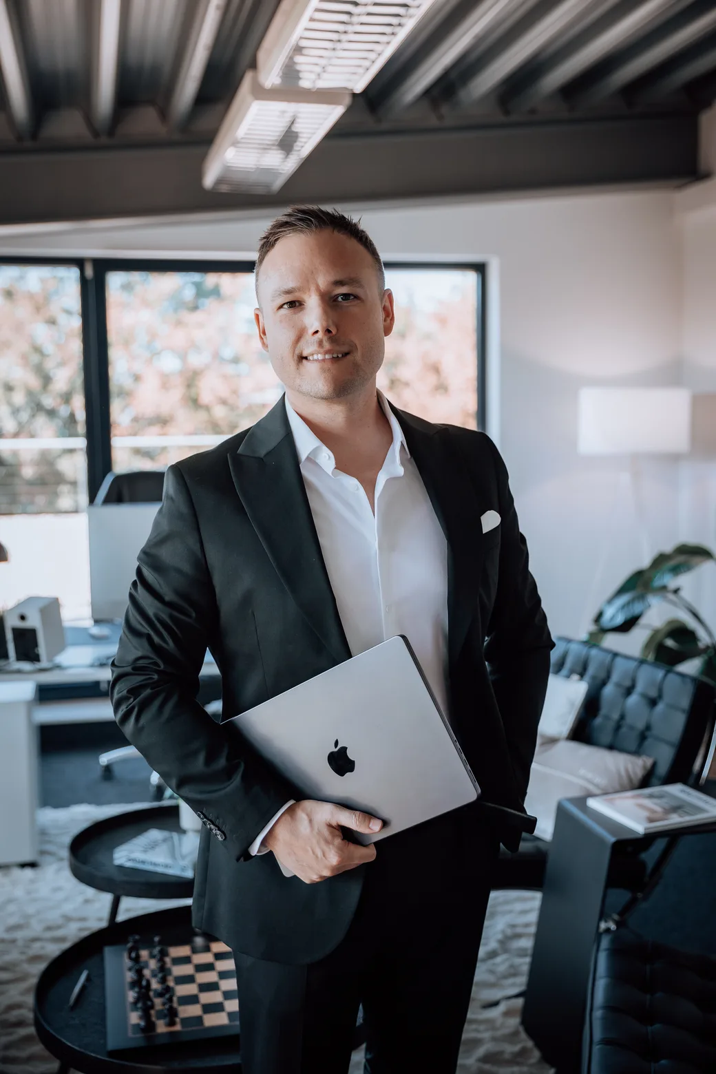 Lennartz Finanzen - Herr Lennartz stehend mit Laptop im Büro